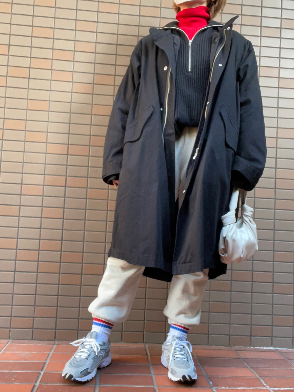 グレー系のスニーカー、ホワイト系のスウェットパンツ、ブラック系のニット/セーターを着用したレディースの冬コーディネートの2枚目の写真