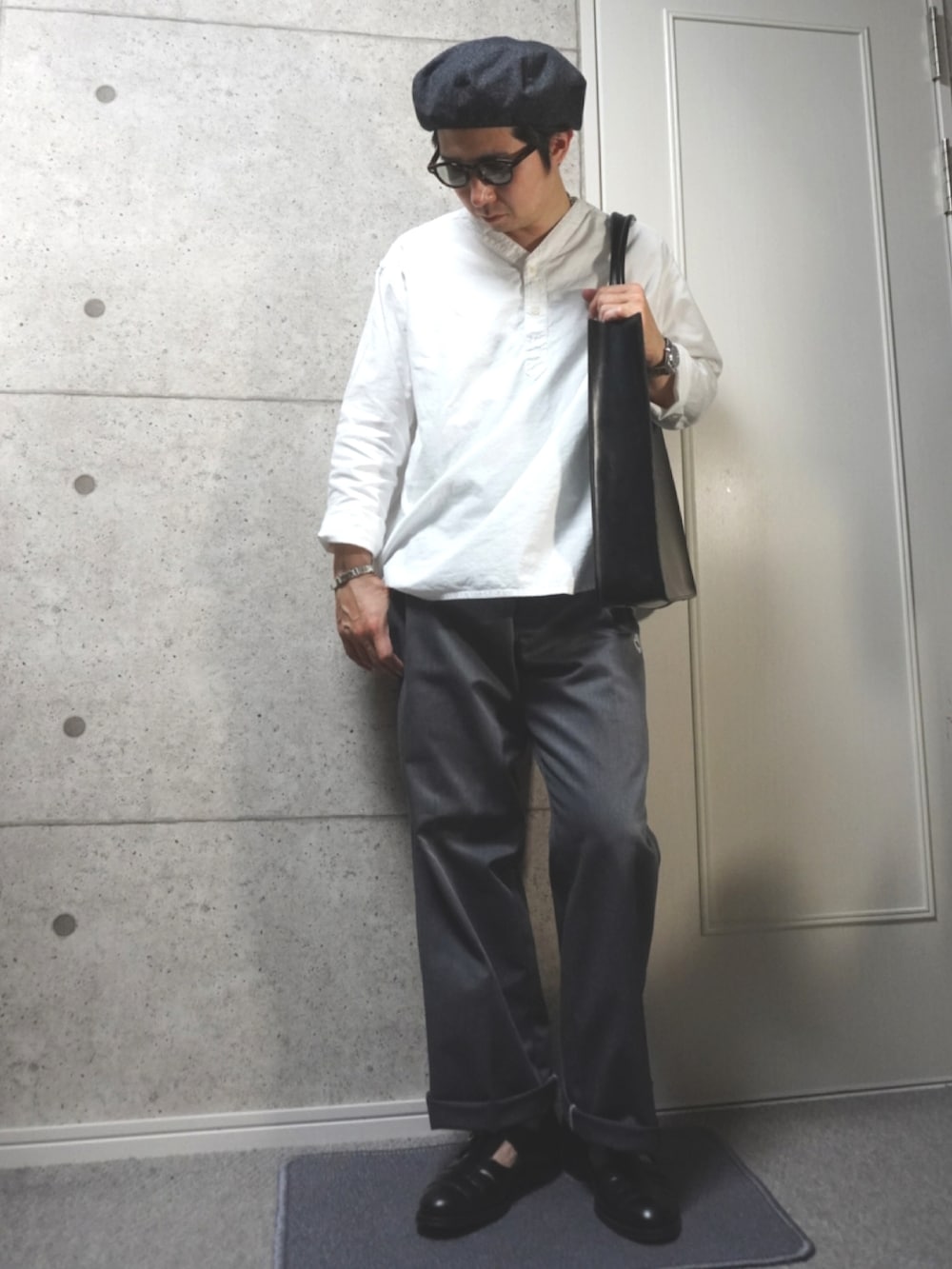 グレー系のチノパンツ、ブラック系のトートバッグ、ブラック系のサンダルを着用したメンズの夏コーディネートの2枚目の写真