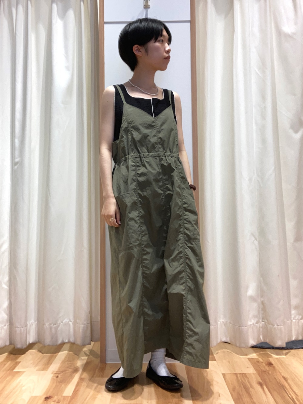 グリーン系のワンピース、ブラック系のタンクトップ、ホワイト系のカーディガン/ボレロを着用したレディースの夏コーディネートの2枚目の写真