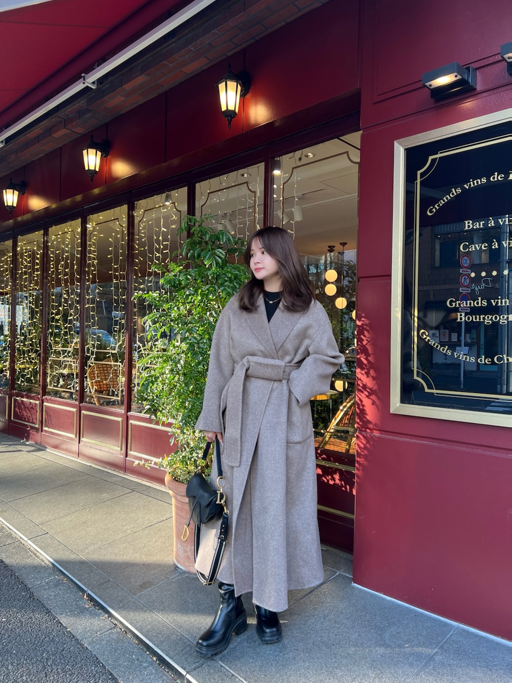 ブラック系のバッグ、ブラック系のトップス、ベージュ系のダウンジャケット/コートを着用したレディースの冬コーディネートの2枚目の写真