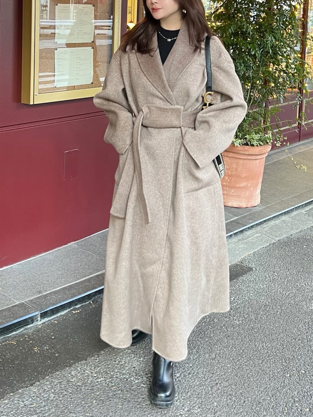 ブラック系のバッグ、ブラック系のトップス、ベージュ系のダウンジャケット/コートを着用したレディースの冬コーディネートの3枚目の写真