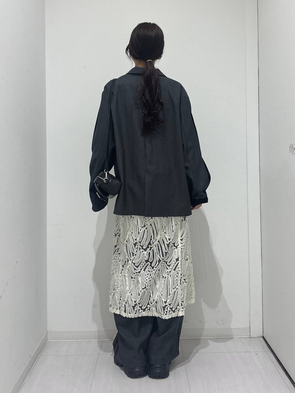 ブラック系のスニーカー、ホワイト系のワンピース、ブラック系のショルダーバッグを着用したレディースの冬コーディネートの5枚目の写真