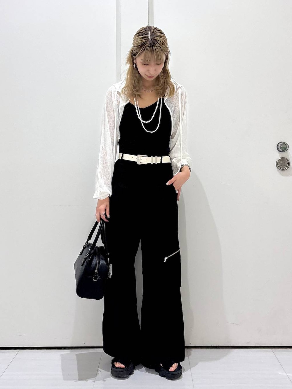 ブラック系のカーゴパンツ、ブラック系のショルダーバッグ、ホワイト系のカーディガン/ボレロを着用したレディースの夏コーディネートの5枚目の写真