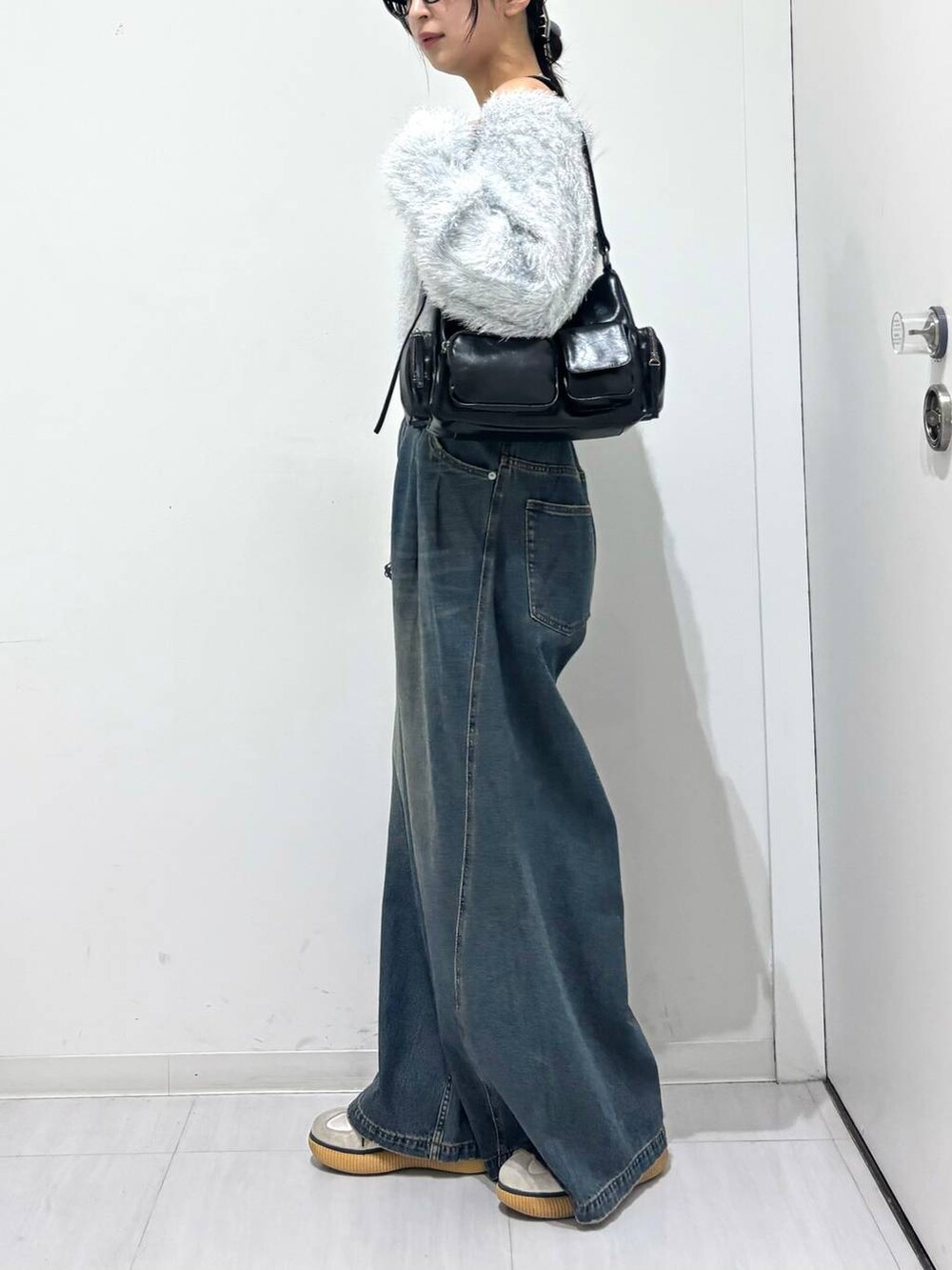 ブルー系のデニムパンツ、ブラック系のショルダーバッグ、ホワイト系のニット/セーターを着用したレディースの秋コーディネートの3枚目の写真