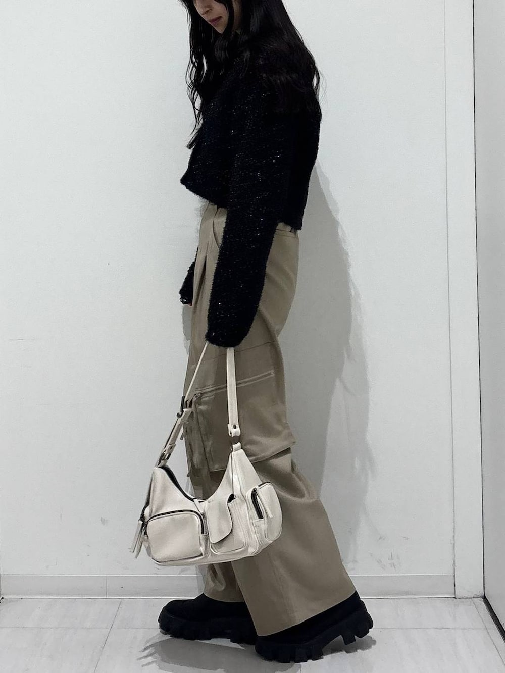 ホワイト系のショルダーバッグ、ベージュ系のカーゴパンツ、ブラック系のカーディガン/ボレロを着用したレディースの冬コーディネートの2枚目の写真