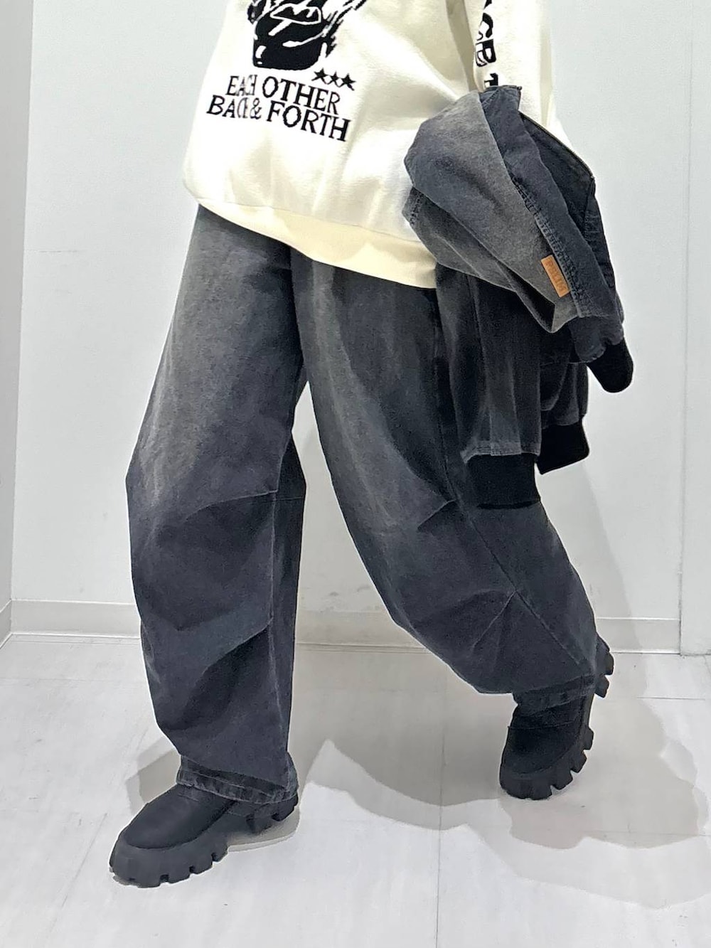 ホワイト系のニット/セーター、ブラック系のデニムジャケット、ブラック系のブーツを着用したレディースの冬コーディネートの5枚目の写真