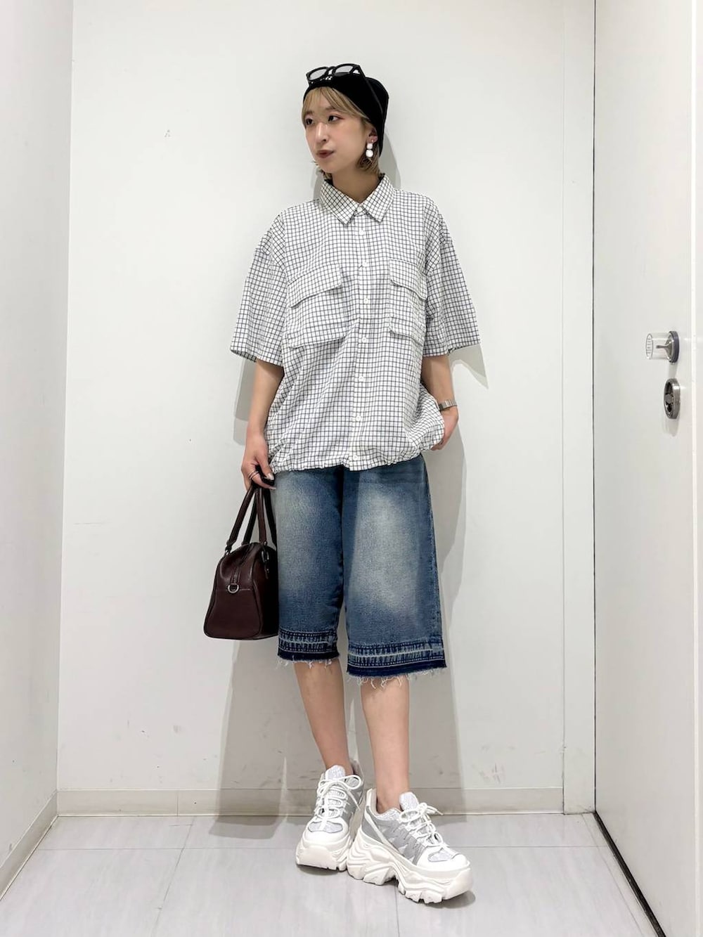 ホワイト系のスニーカー、ブラウン系のショルダーバッグ、ブルー系のデニムパンツを着用したレディースの夏コーディネートの2枚目の写真