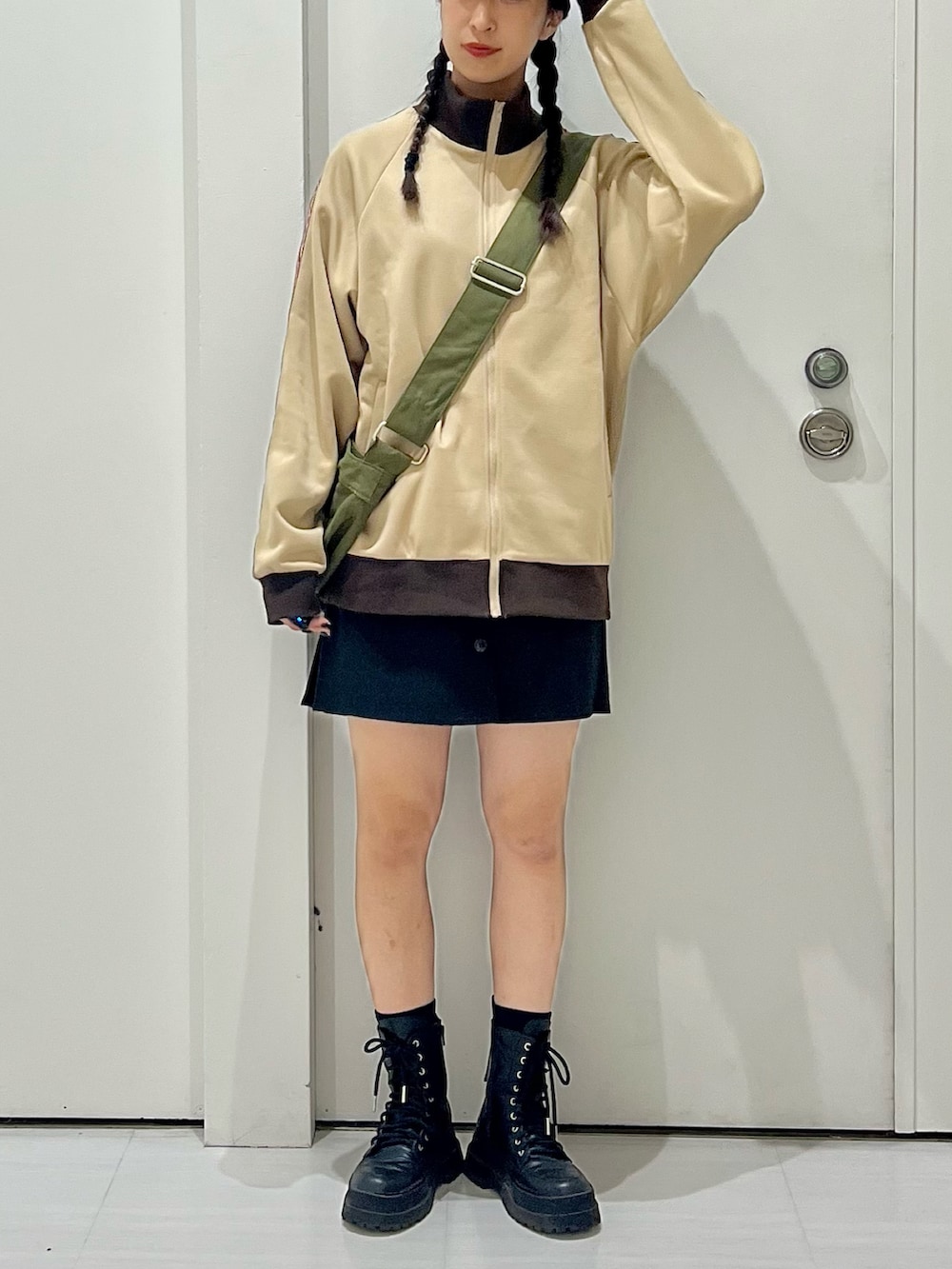 ベージュ系のセットアップ、グリーン系のショルダーバッグ、ブラック系のブーツを着用したレディースの秋コーディネートの2枚目の写真