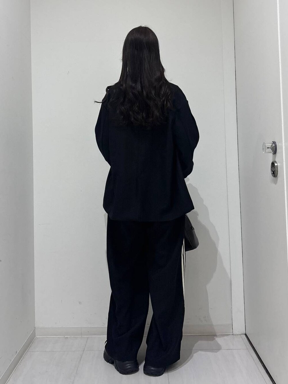 ブラック系のスニーカー、ブラック系のボストンバッグ、ブラック系のテーラードジャケットを着用したレディースの冬コーディネートの4枚目の写真