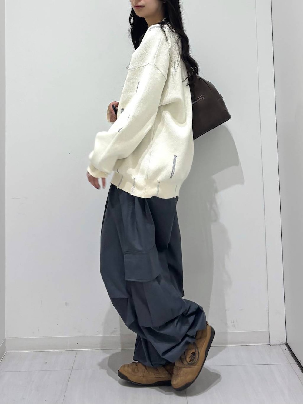 グレー系のカーゴパンツ、ホワイト系のニット/セーター、ブラウン系のボストンバッグを着用したレディースの冬コーディネートの5枚目の写真