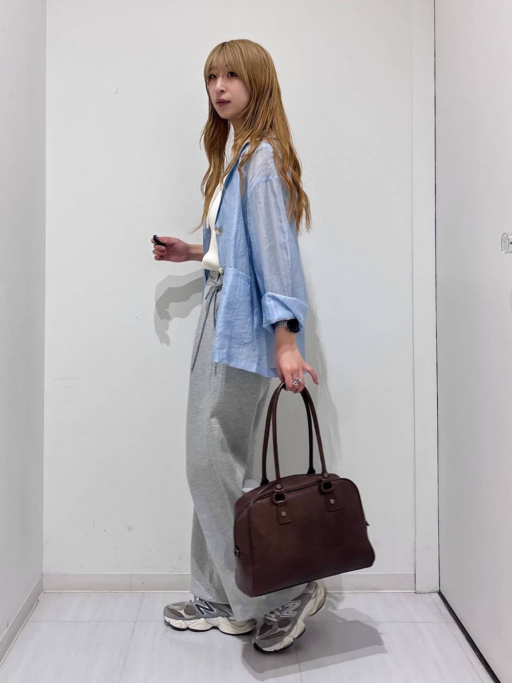 ブラウン系のボストンバッグ、ホワイト系のタンクトップ、ブルー系のテーラードジャケットを着用したレディースの春コーディネートの7枚目の写真