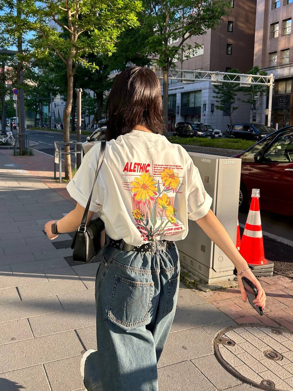 ホワイト系のスニーカー、ブラック系のハンドバッグ、ブルー系のデニムパンツを着用したレディースの夏コーディネートの2枚目の写真