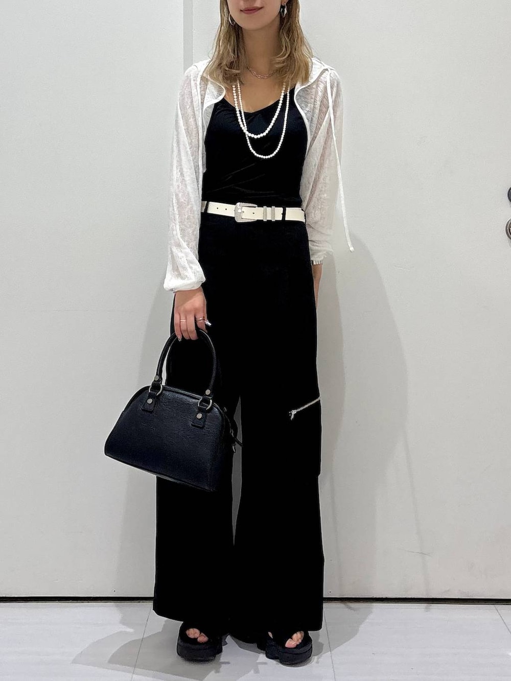 ブラック系のカーゴパンツ、ブラック系のショルダーバッグ、ホワイト系のカーディガン/ボレロを着用したレディースの夏コーディネートの2枚目の写真