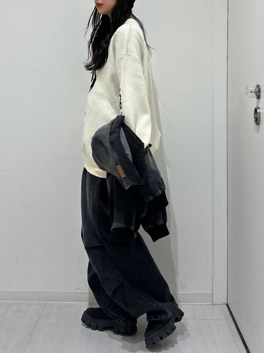 ホワイト系のニット/セーター、ブラック系のデニムジャケット、ブラック系のブーツを着用したレディースの冬コーディネートの6枚目の写真