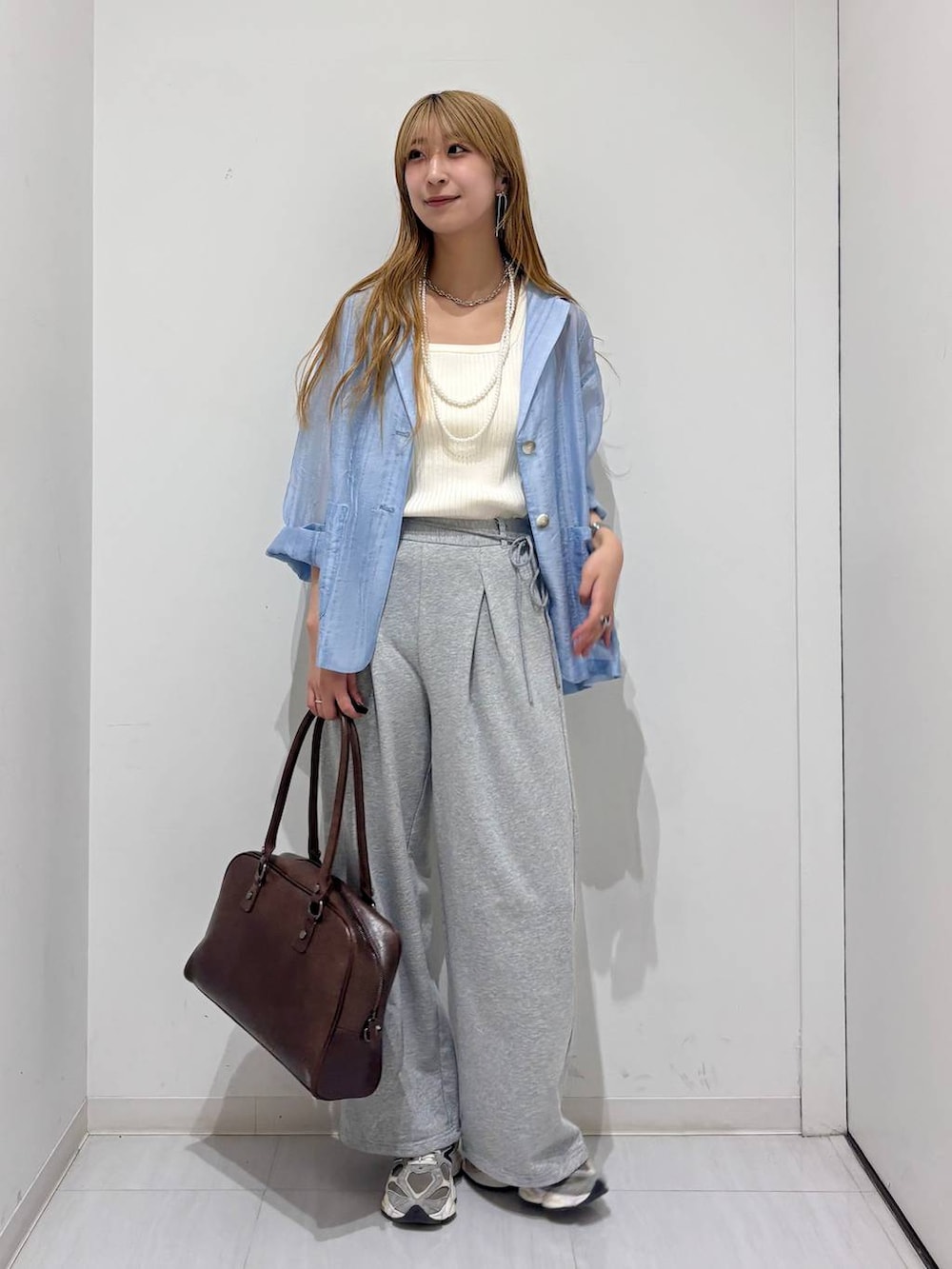 ブラウン系のボストンバッグ、ホワイト系のタンクトップ、ブルー系のテーラードジャケットを着用したレディースの春コーディネートの2枚目の写真