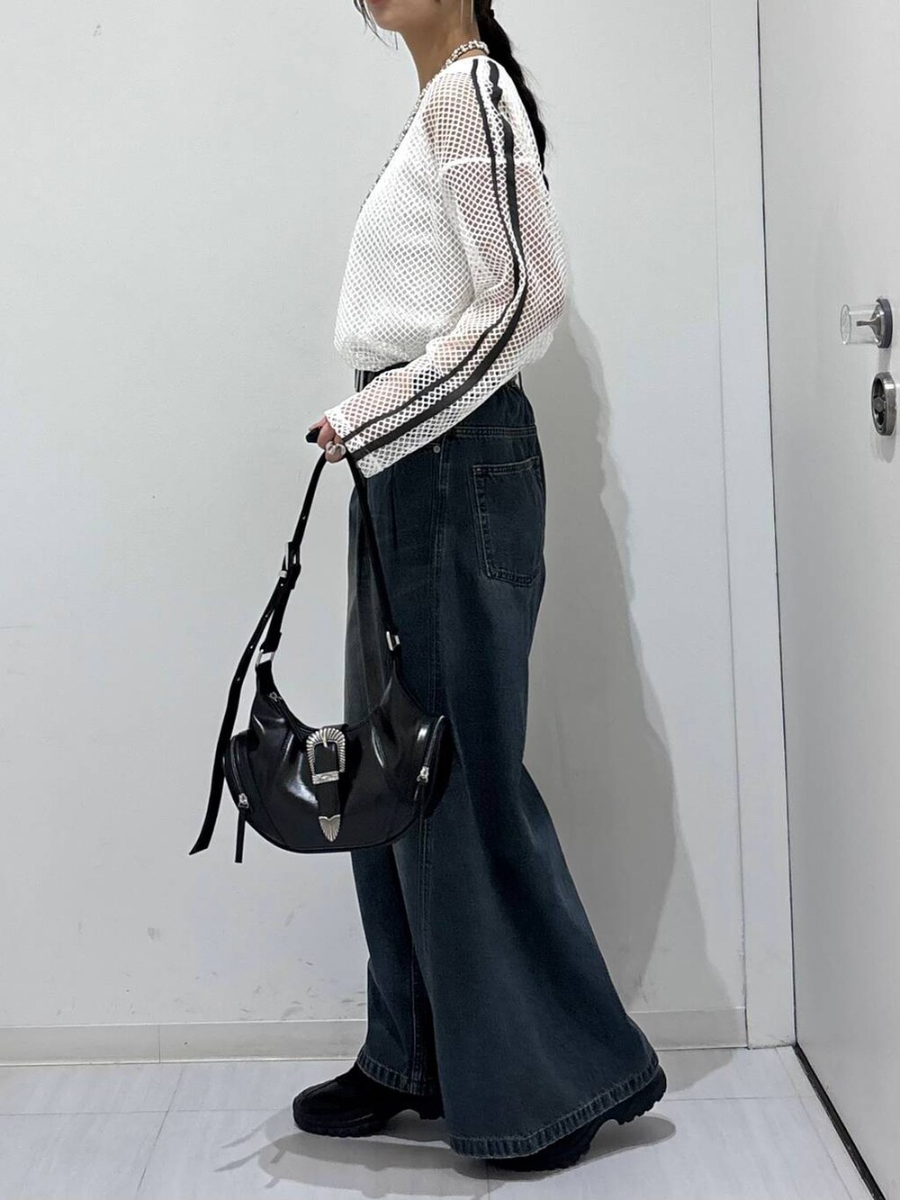 ブルー系のデニムパンツ、ブラック系のスニーカー、ホワイト系のTシャツ/カットソーを着用したレディースの春コーディネートの4枚目の写真