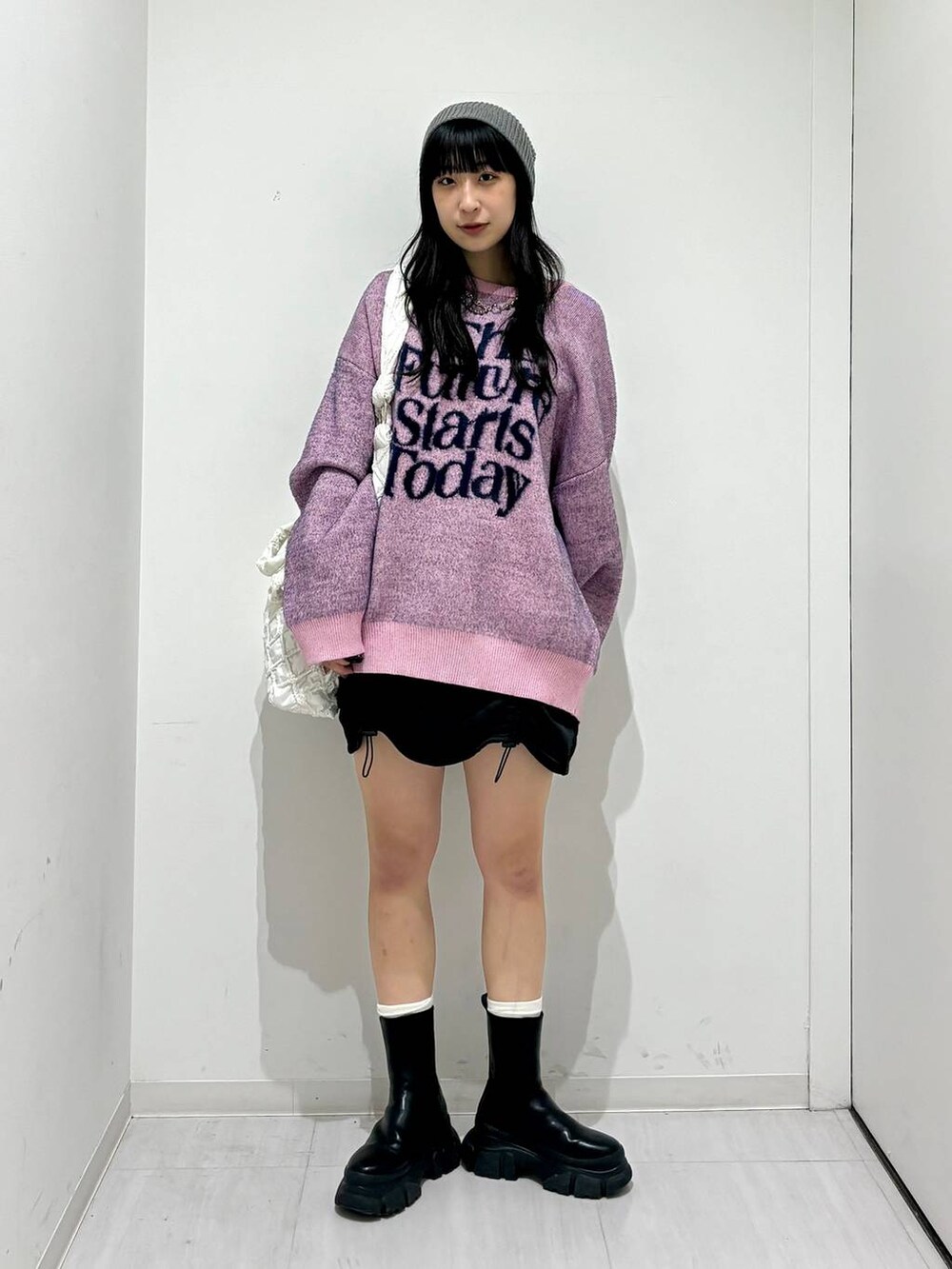 ブラック系のブーツ、ピンク系のニット/セーター、ホワイト系のショルダーバッグを着用したレディースの冬コーディネートの5枚目の写真