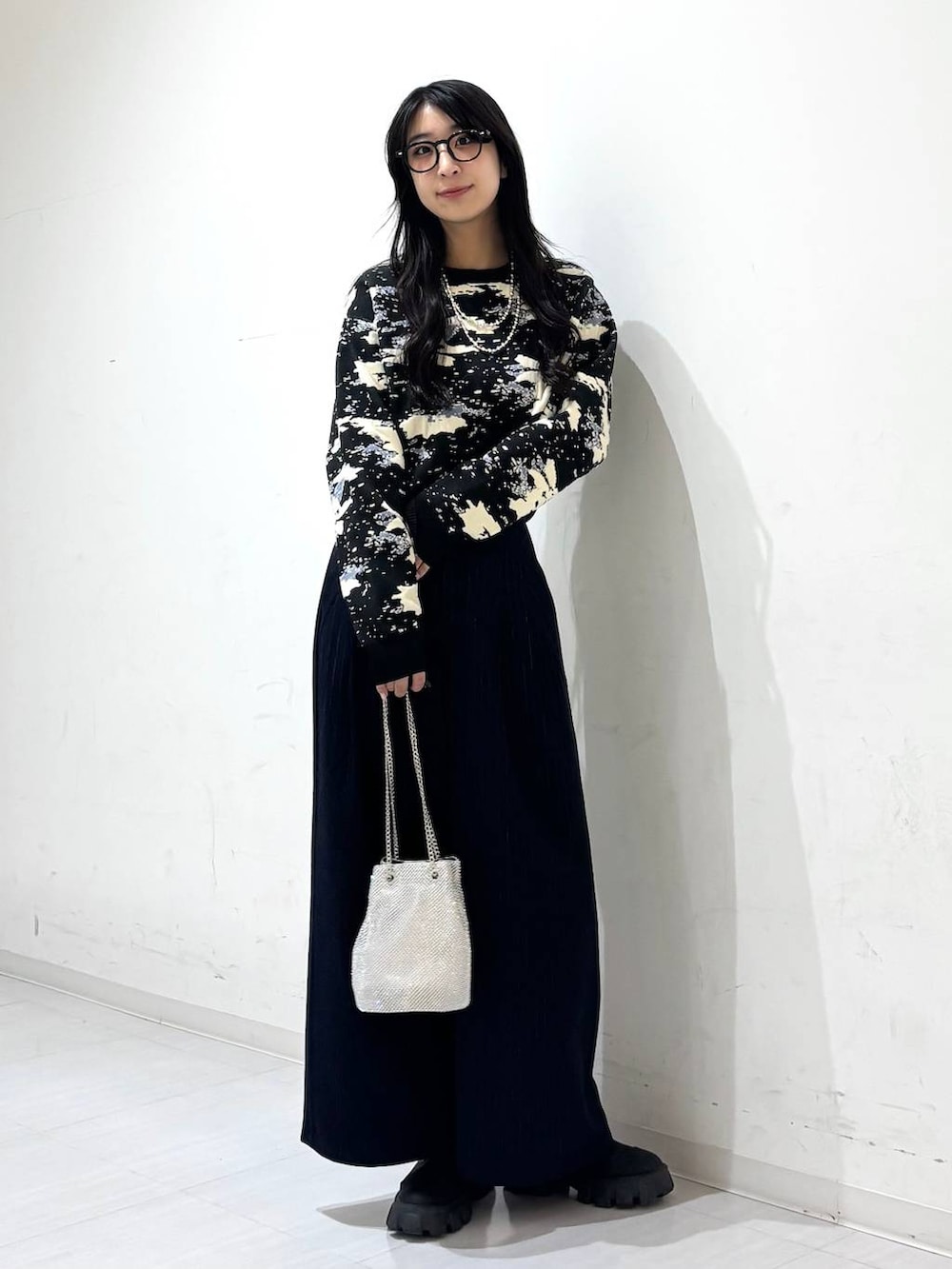 シルバー系のショルダーバッグ、ブルー系のスラックス、ブラック系のニット/セーターを着用したレディースの冬コーディネートの4枚目の写真