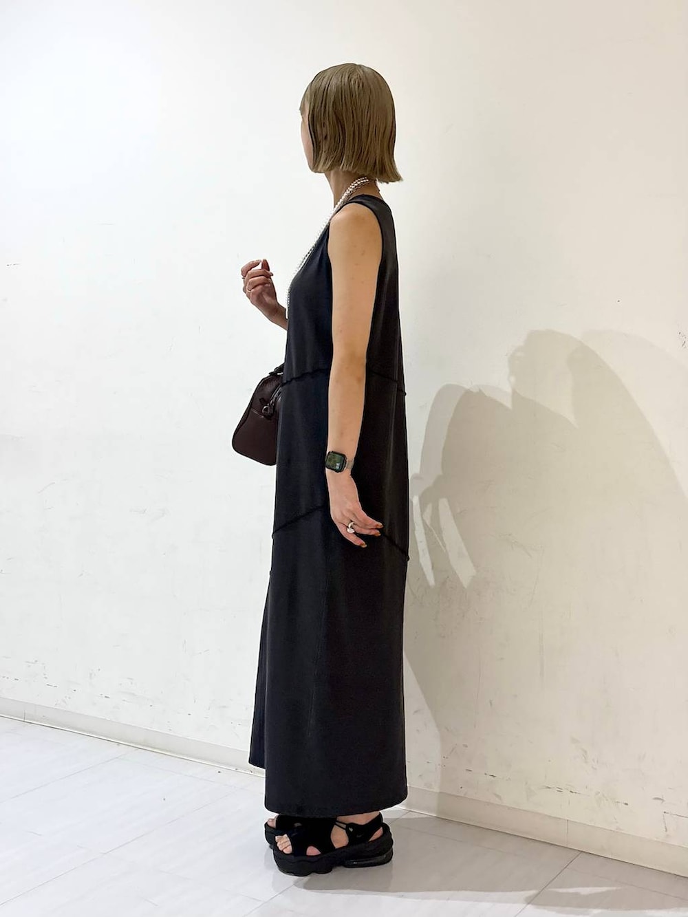 ブラック系のワンピース、ブラウン系のショルダーバッグ、ホワイト系のネックレスを着用したレディースの夏コーディネートの4枚目の写真