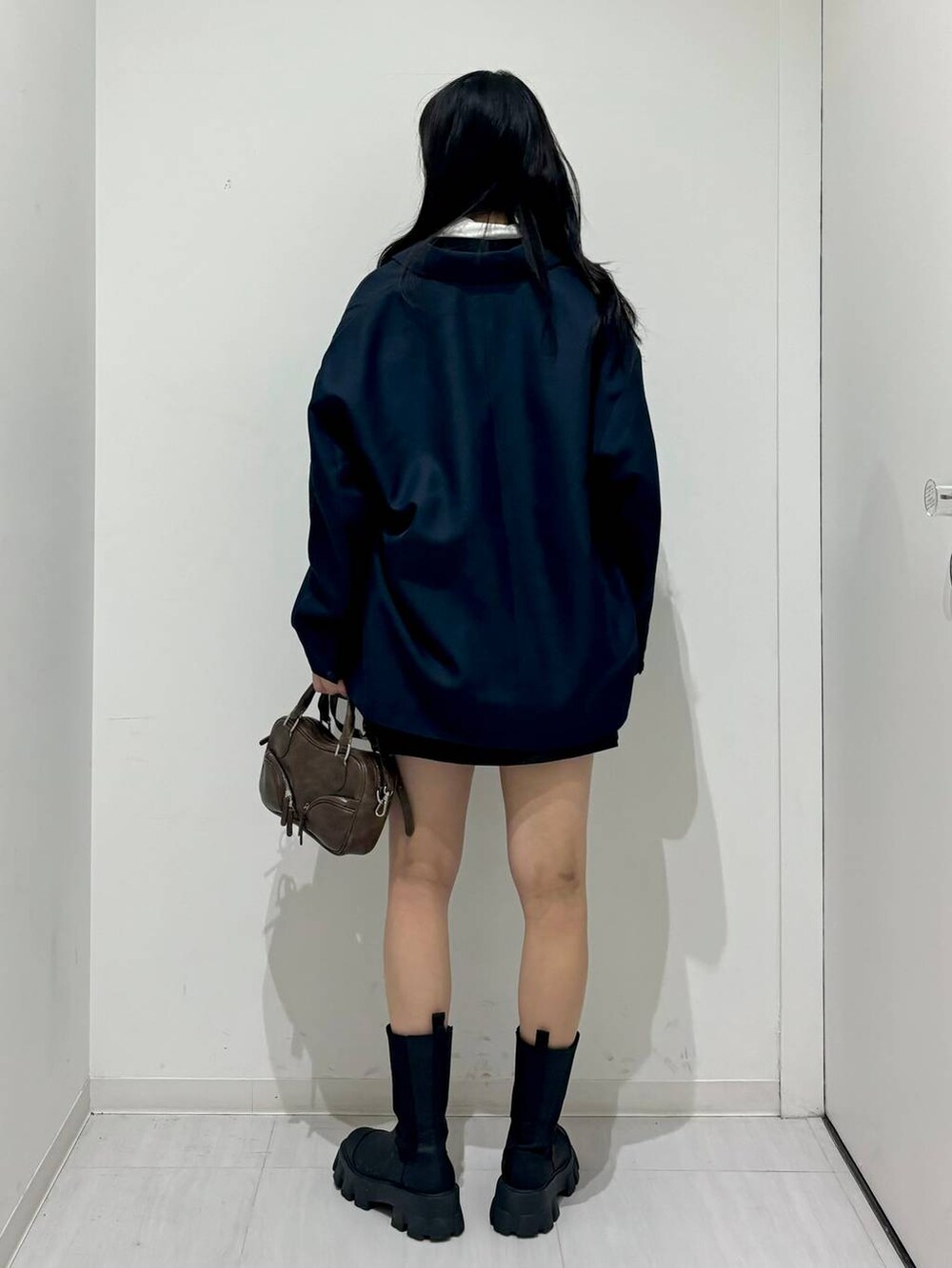 ブルー系のテーラードジャケット、ブラック系のスウェット、ブラック系のブーツを着用したレディースの冬コーディネートの4枚目の写真