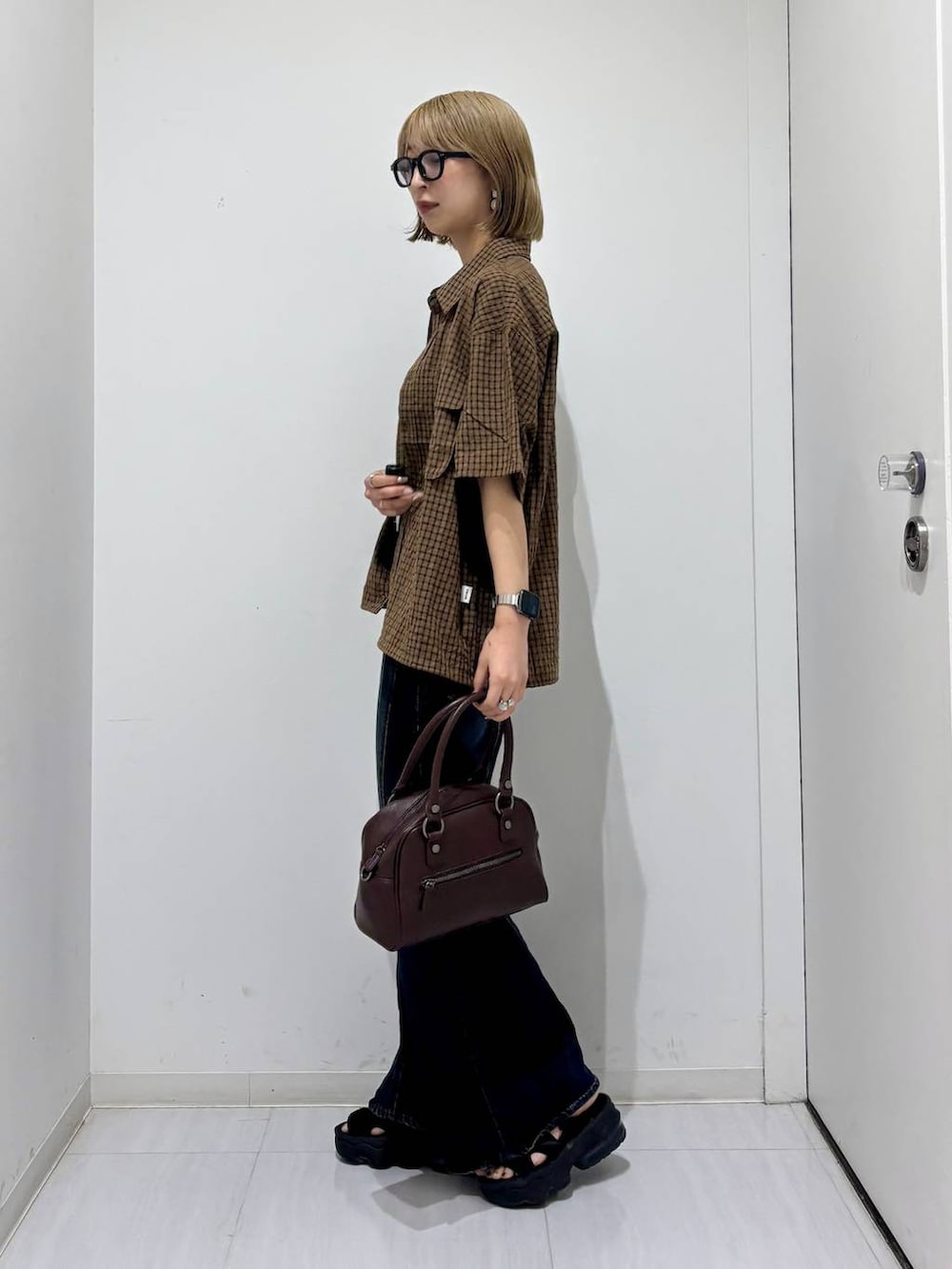 ブラウン系のショルダーバッグ、ブルー系のデニムパンツ、ブラウン系のシャツ/ブラウスを着用したレディースの夏コーディネートの3枚目の写真