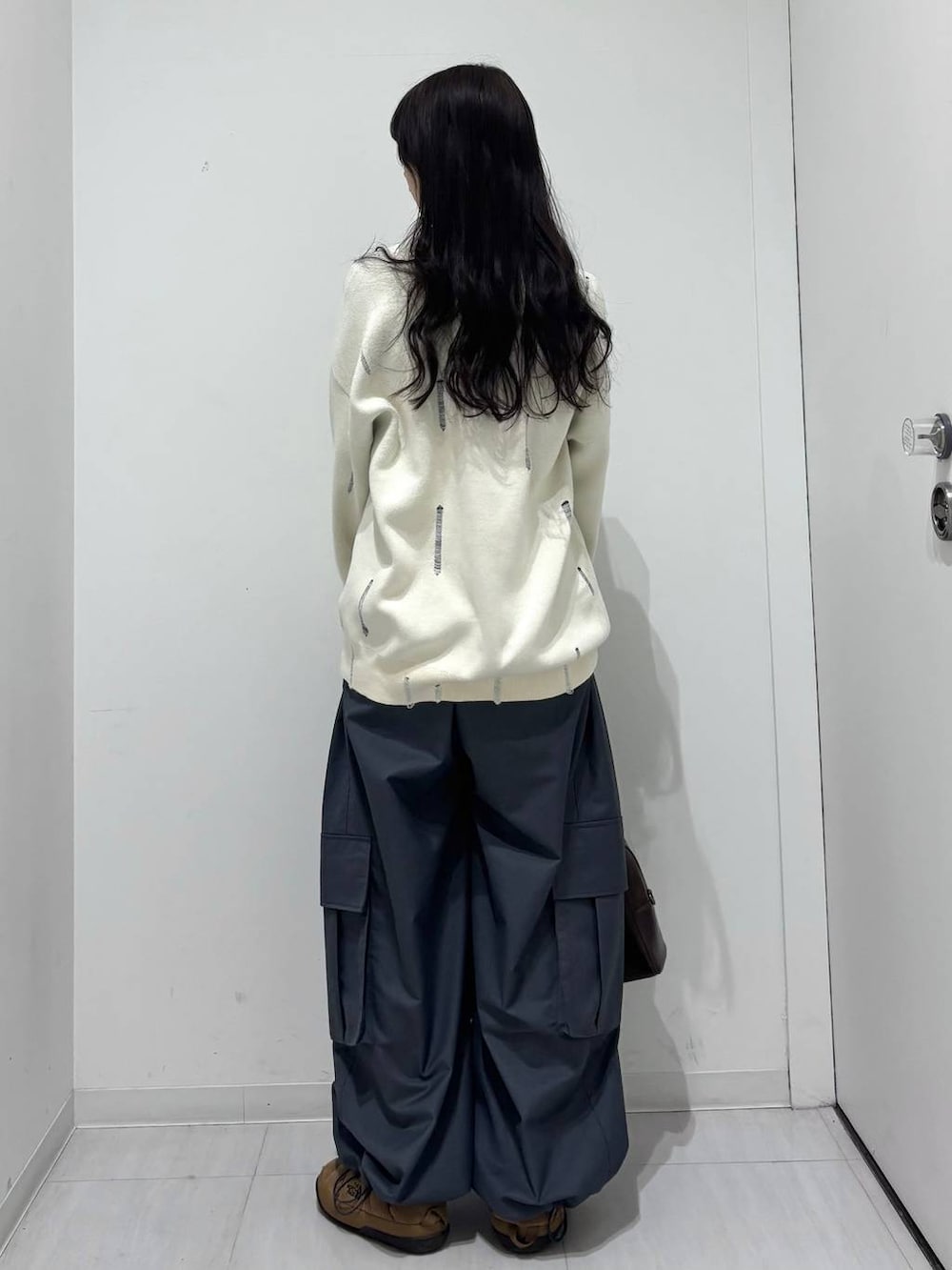 グレー系のカーゴパンツ、ホワイト系のニット/セーター、ブラウン系のボストンバッグを着用したレディースの冬コーディネートの6枚目の写真