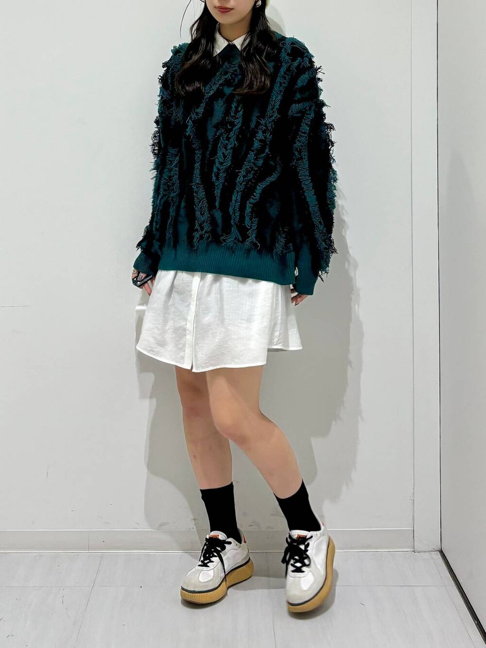 グリーン系のニット/セーター、ブラック系のその他パンツ、ホワイト系のシャツ/ブラウスを着用したレディースの秋コーディネートの3枚目の写真