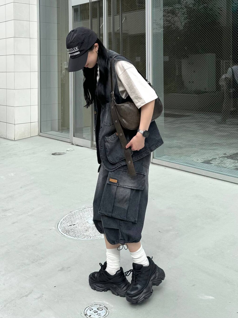 ブラック系のスニーカー、ベージュ系のTシャツ/カットソー、ブラック系のデニムパンツを着用したレディースの夏コーディネートの2枚目の写真