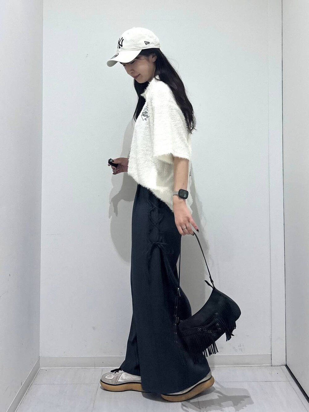 ブラック系のショルダーバッグ、グレー系のスラックス、ホワイト系のポロシャツを着用したレディースの春コーディネートの5枚目の写真