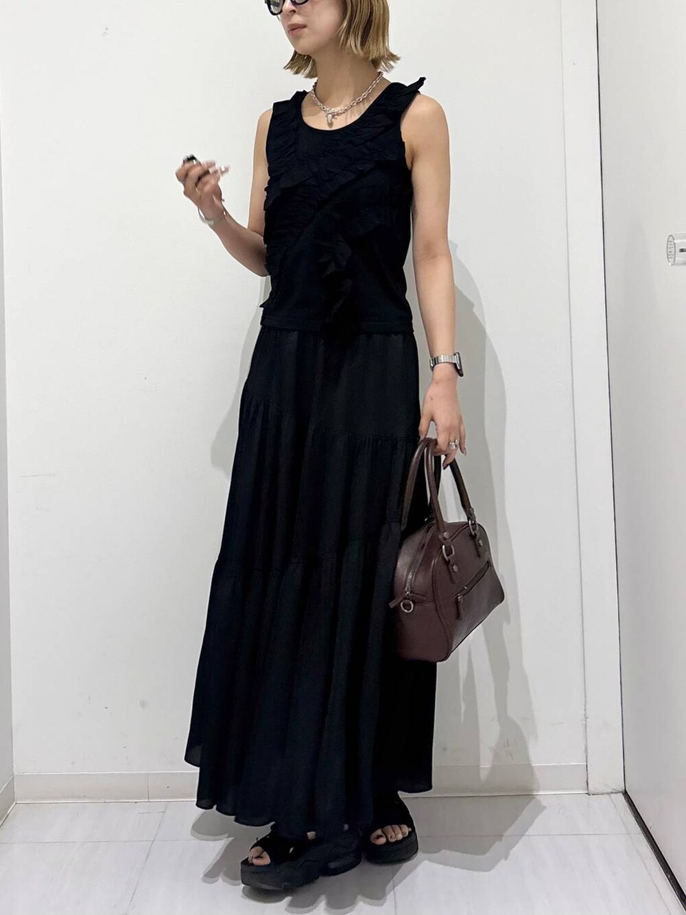 ブラウン系のショルダーバッグ、ブラック系のタンクトップ、ブラック系のスカートを着用したレディースの夏コーディネートの3枚目の写真