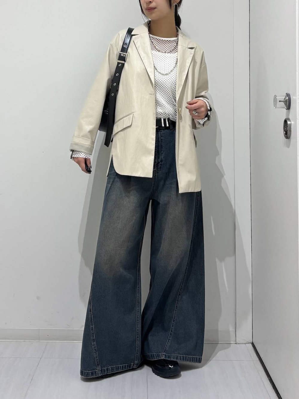 ブルー系のデニムパンツ、ブラック系のスニーカー、ホワイト系のTシャツ/カットソーを着用したレディースの春コーディネートの2枚目の写真