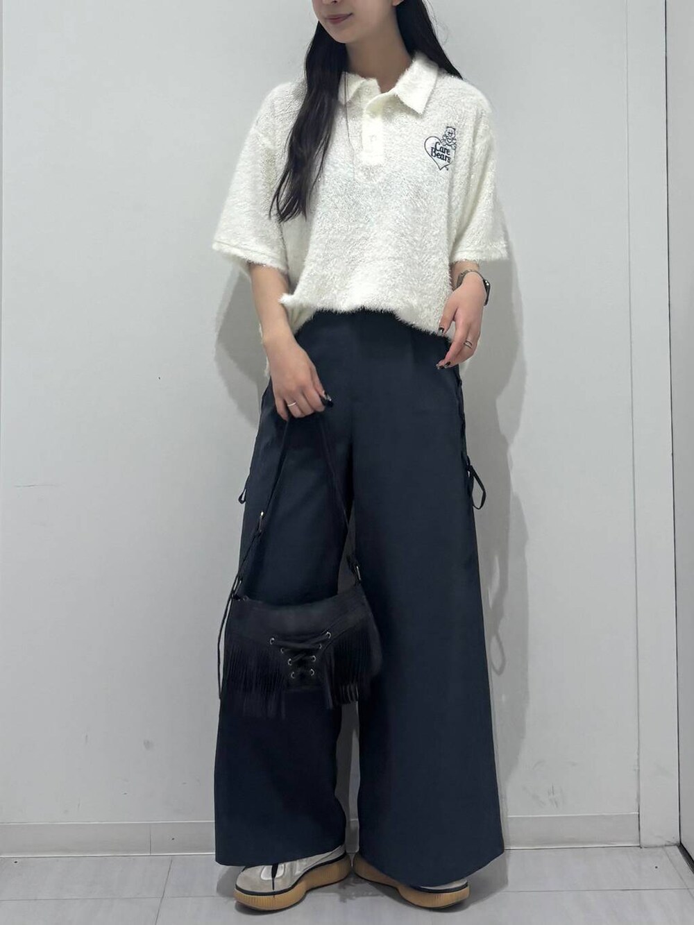 ブラック系のショルダーバッグ、グレー系のスラックス、ホワイト系のポロシャツを着用したレディースの春コーディネートの4枚目の写真