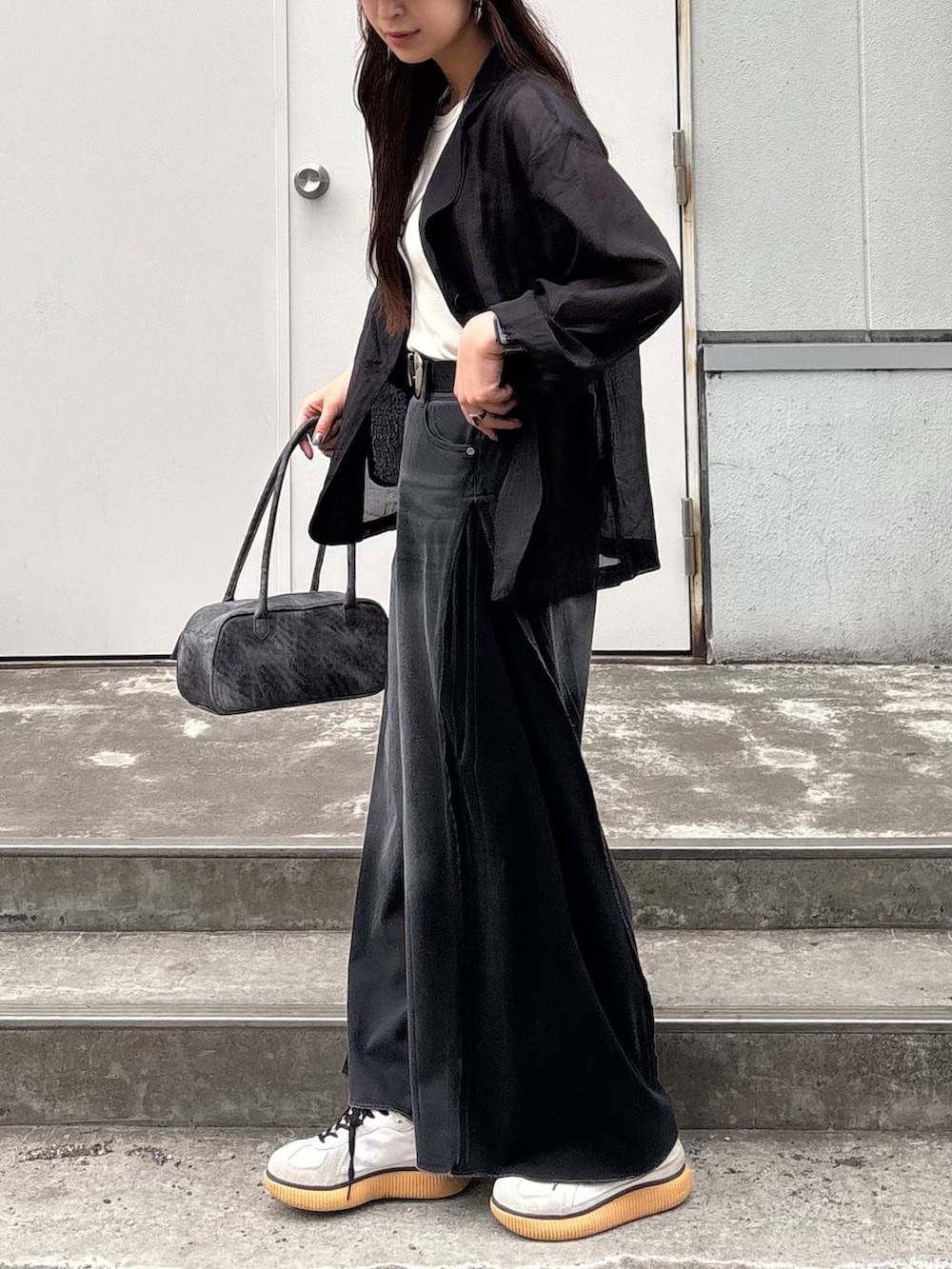 ブラック系のボストンバッグ、ホワイト系のタンクトップ、ブラック系のデニムパンツを着用したレディースの春コーディネートの3枚目の写真