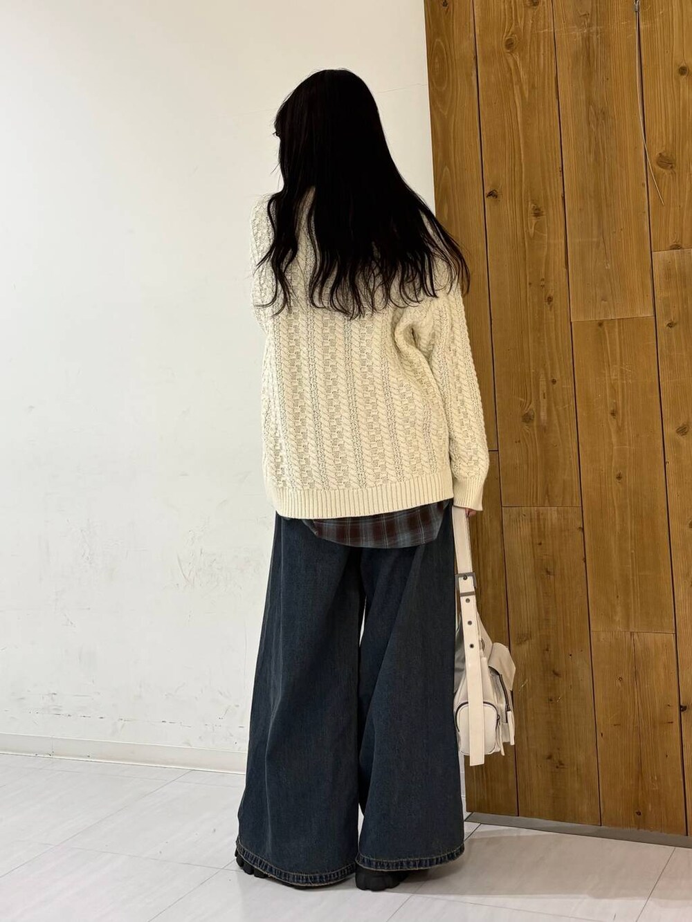 ブルー系のデニムパンツ、ホワイト系のショルダーバッグ、ホワイト系のニット/セーターを着用したレディースの冬コーディネートの3枚目の写真