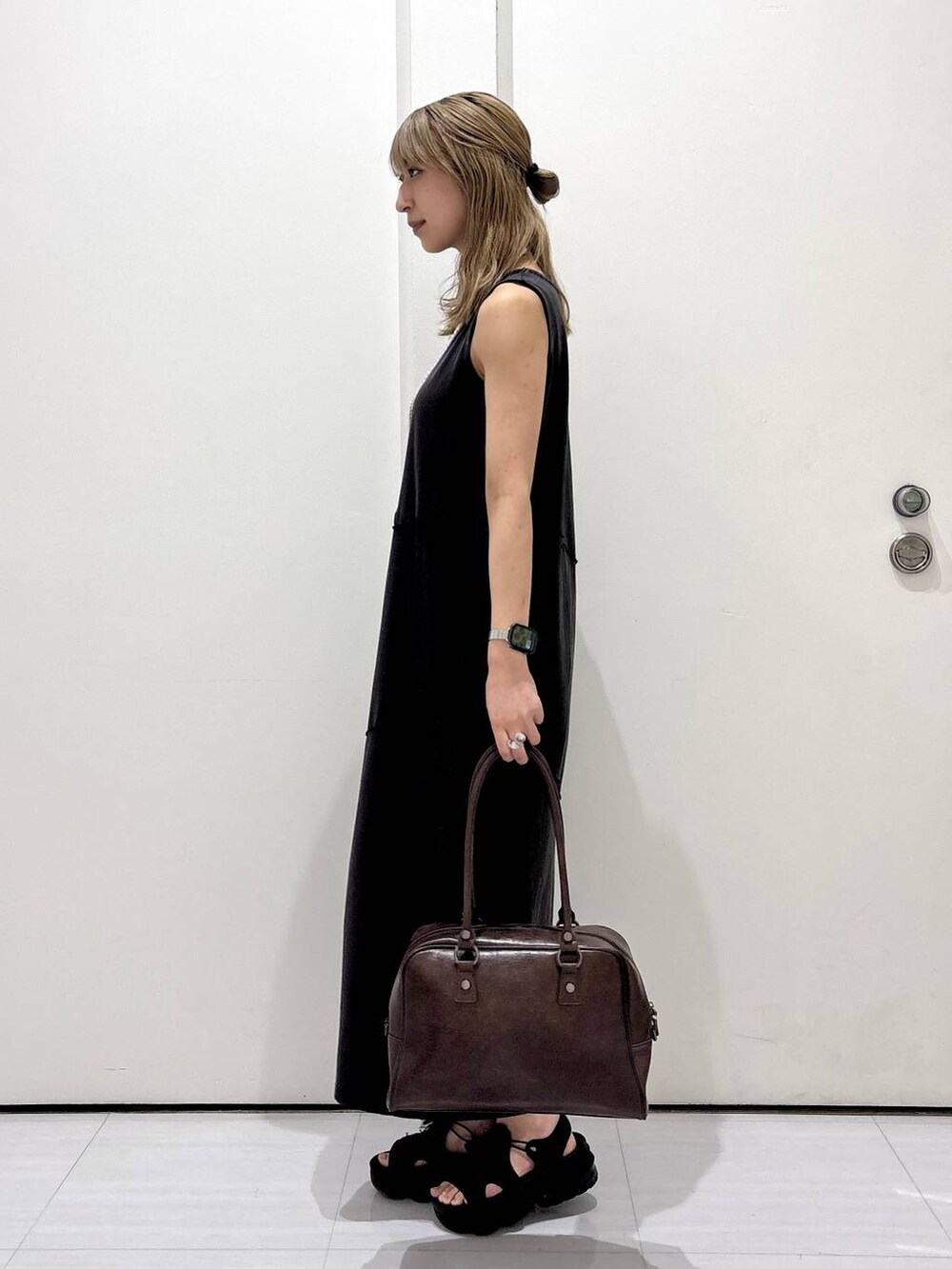 ブラウン系のボストンバッグ、ブラック系のワンピース、ホワイト系のネックレスを着用したレディースの春コーディネートの3枚目の写真