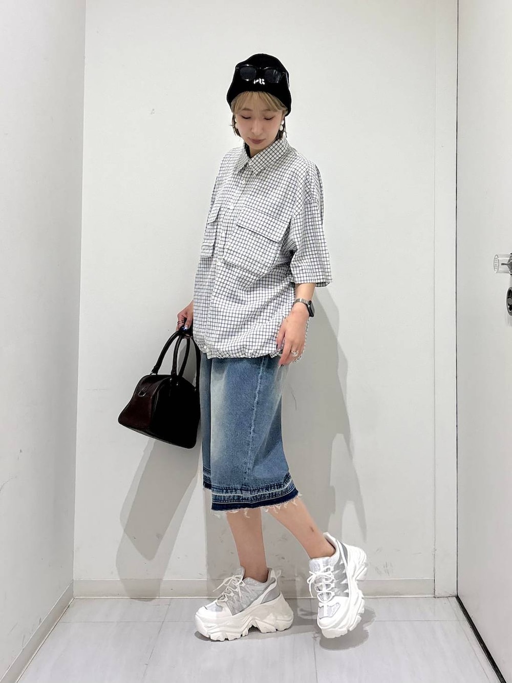 ホワイト系のスニーカー、ブラウン系のショルダーバッグ、ブルー系のデニムパンツを着用したレディースの夏コーディネートの3枚目の写真