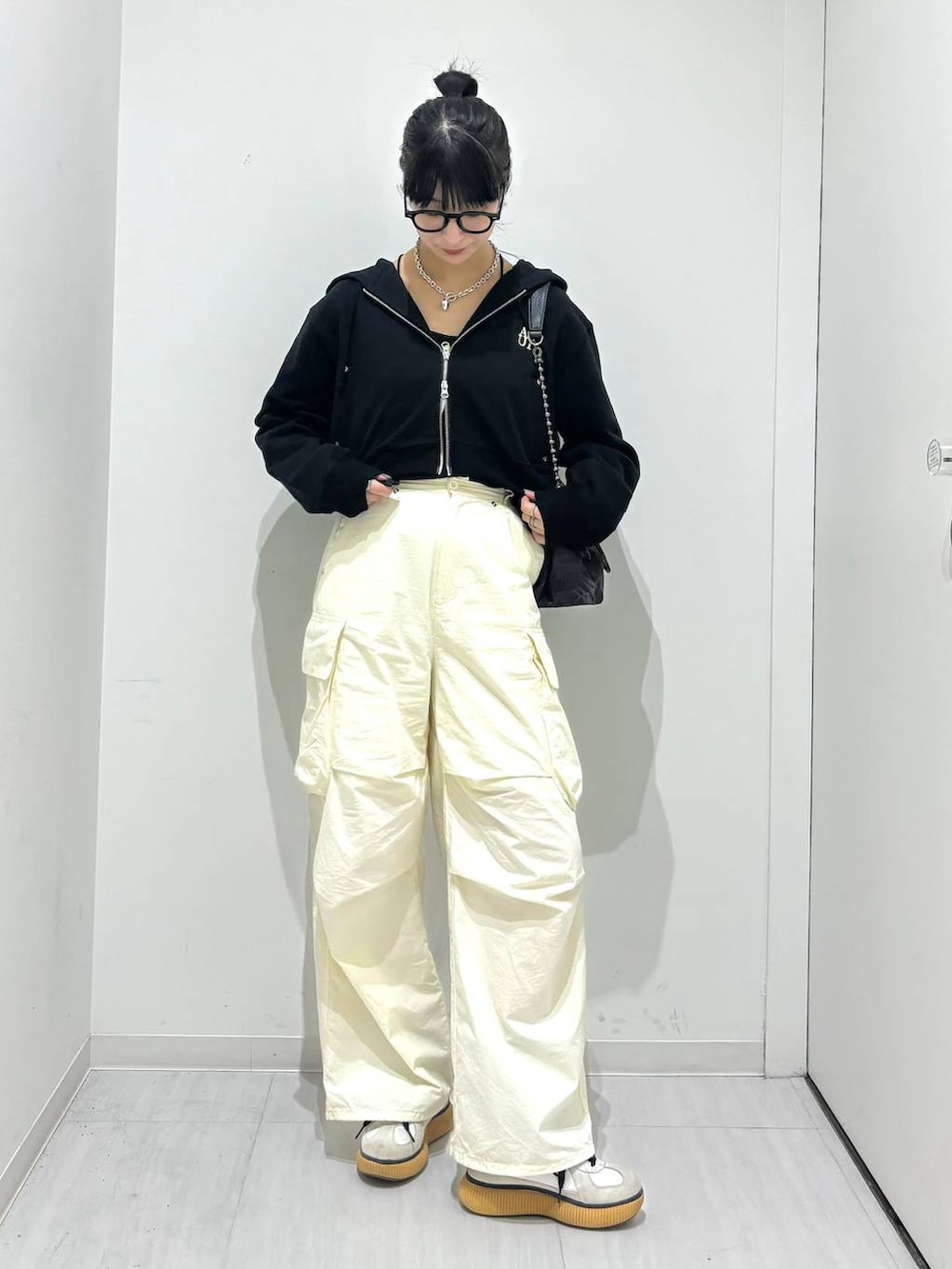 ブラック系のパーカー、ブラック系のショルダーバッグ、ホワイト系のカーゴパンツを着用したレディースの春コーディネートの5枚目の写真