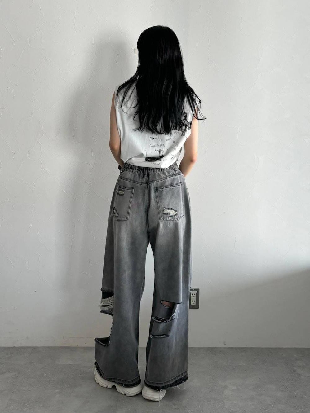 ブラック系のデニムパンツ、ホワイト系のスニーカー、ホワイト系のTシャツ/カットソーを着用したレディースの春コーディネートの4枚目の写真