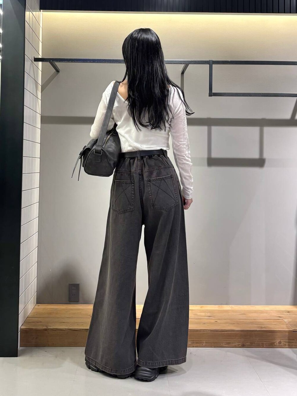 ブラック系のデニムパンツ、ブラック系のショルダーバッグ、ブラック系のブーツを着用したレディースの秋コーディネートの2枚目の写真