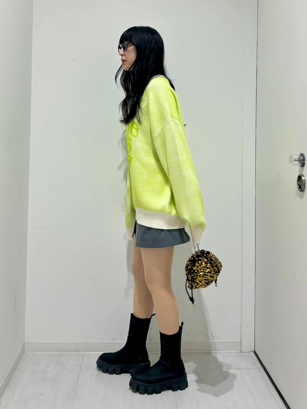 ブラック系のブーツ、ホワイト系のニット/セーター、ゴールド系のショルダーバッグを着用したレディースの冬コーディネートの3枚目の写真