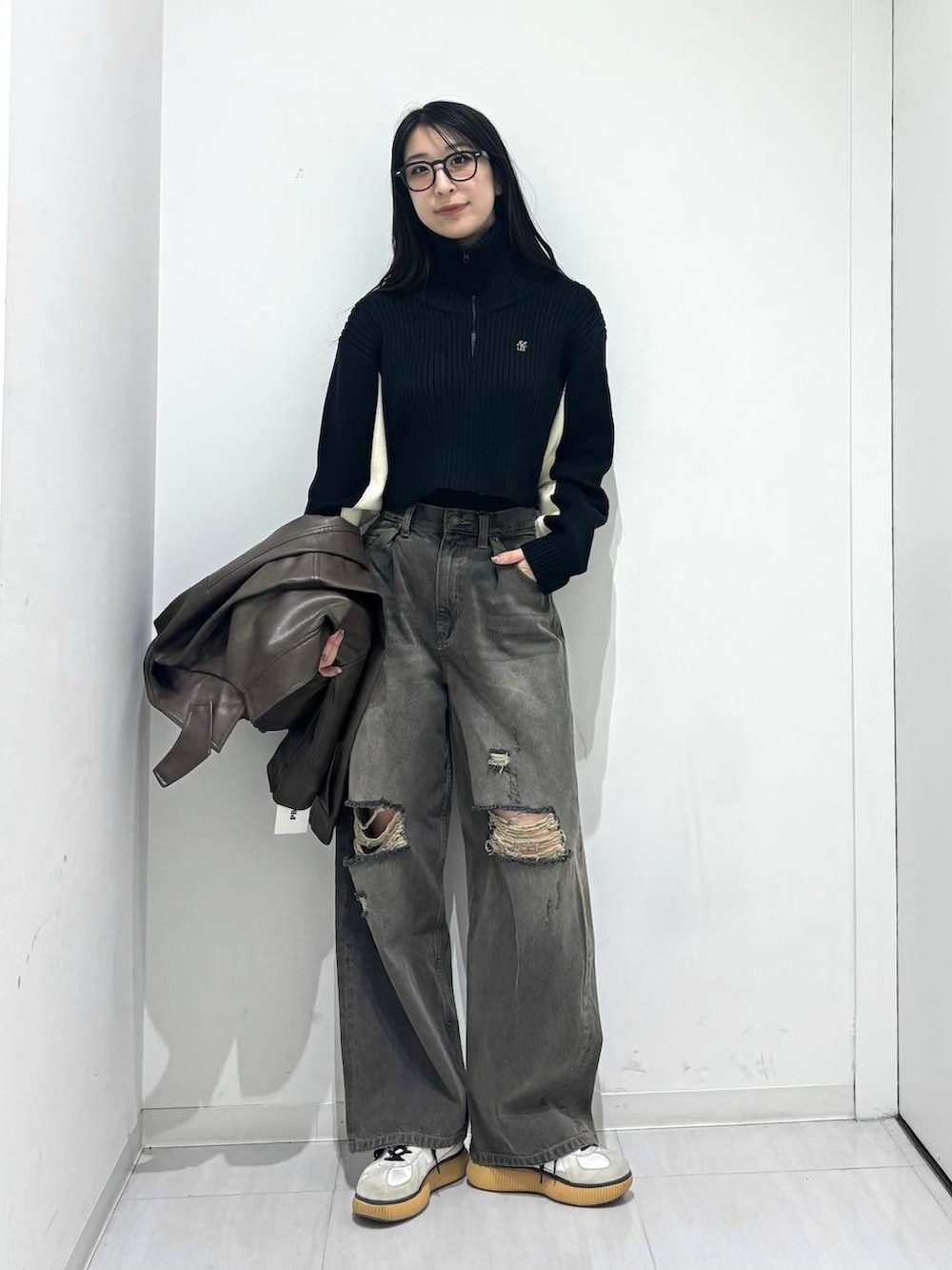 ブラウン系のブルゾン、ブラック系のデニムパンツ、ブラック系のニット/セーターを着用したレディースの秋コーディネートの4枚目の写真