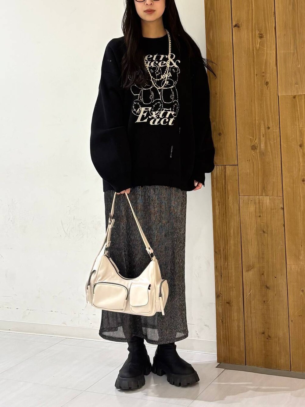 ホワイト系のショルダーバッグ、ブラック系のニット/セーター、ブラック系のスカートを着用したレディースの冬コーディネートの2枚目の写真