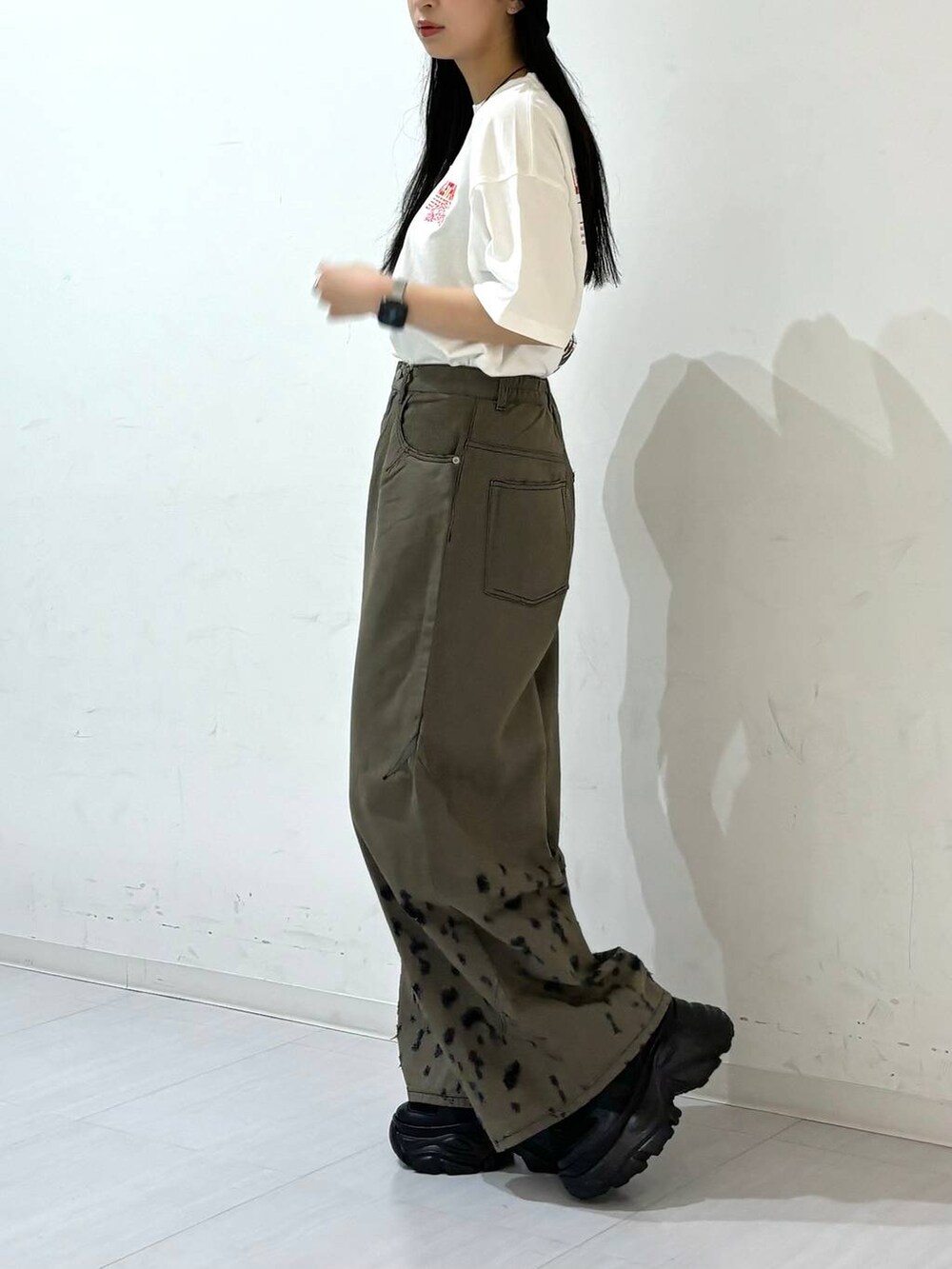 ブラック系のスニーカー、ホワイト系のTシャツ/カットソー、ブラック系のデニムパンツを着用したレディースの夏コーディネートの3枚目の写真