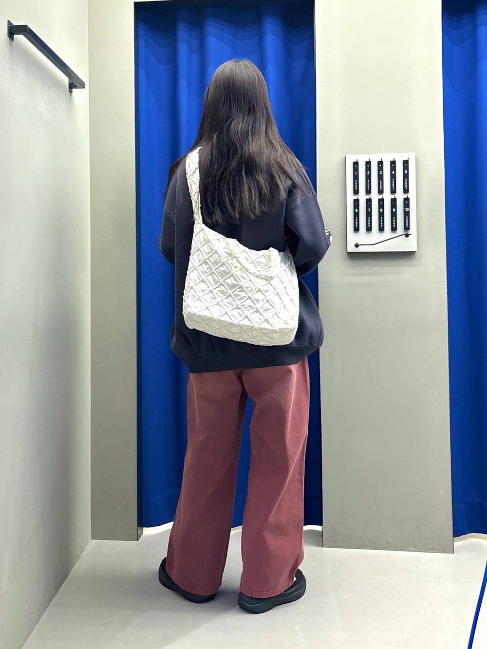 ホワイト系のショルダーバッグ、グレー系のニット/セーター、レッド系のデニムパンツを着用したレディースの冬コーディネートの3枚目の写真