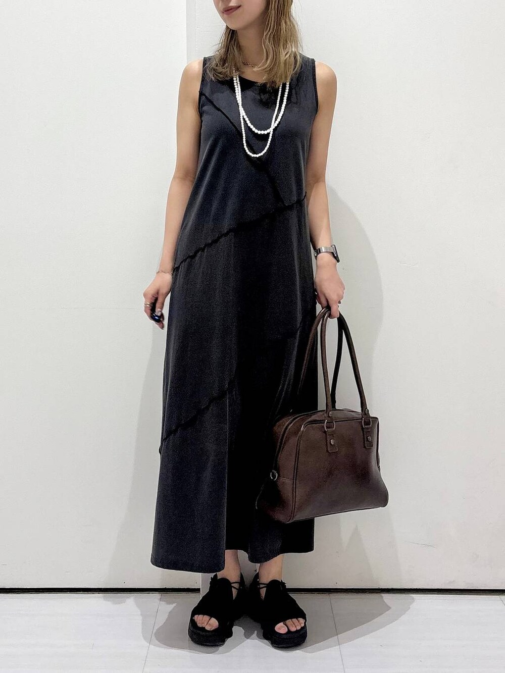 ブラウン系のボストンバッグ、ブラック系のワンピース、ホワイト系のネックレスを着用したレディースの春コーディネートの2枚目の写真