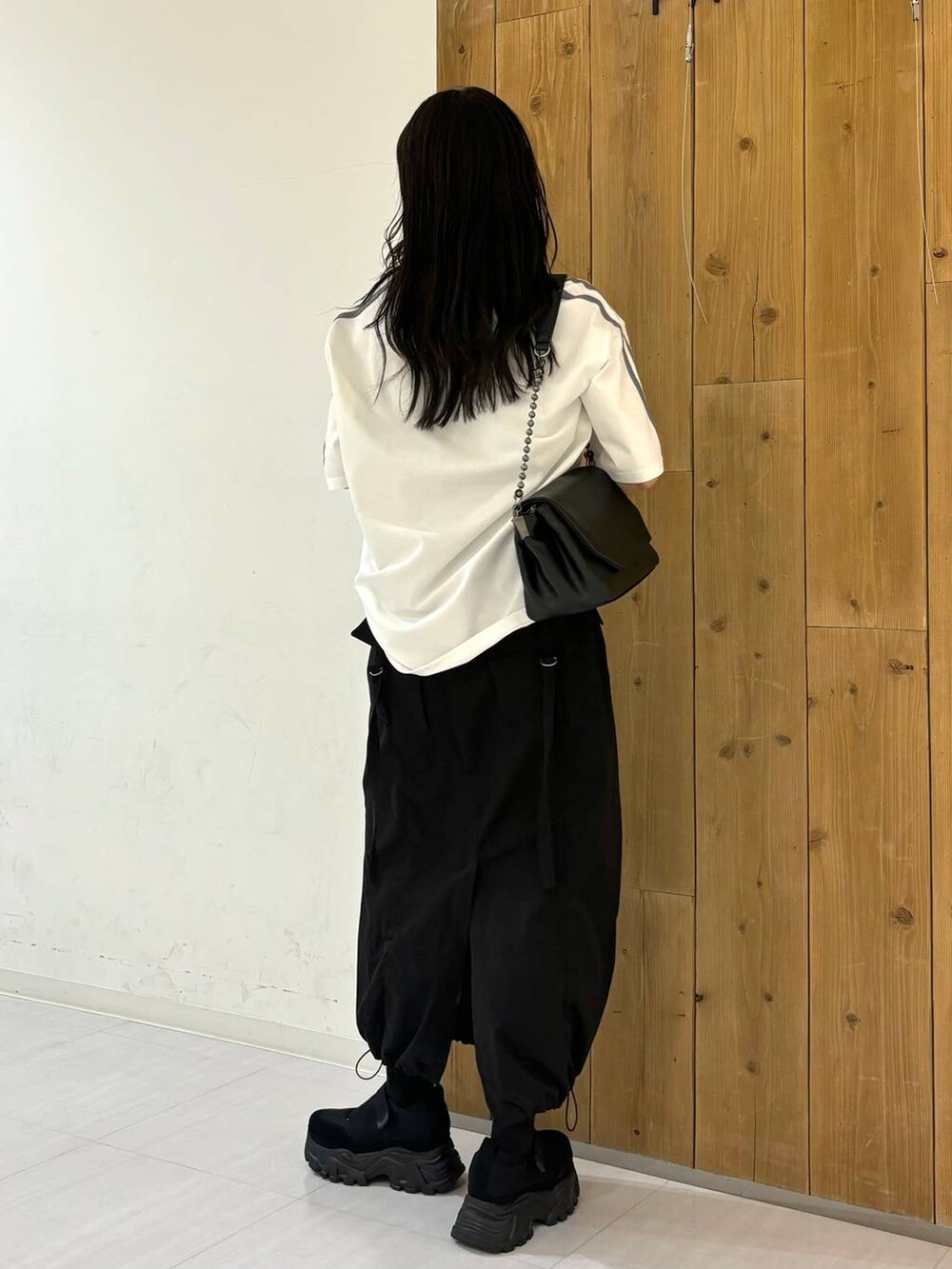 ブラック系のショルダーバッグ、ホワイト系のTシャツ/カットソー、ブラック系のスニーカーを着用したレディースの春コーディネートの4枚目の写真