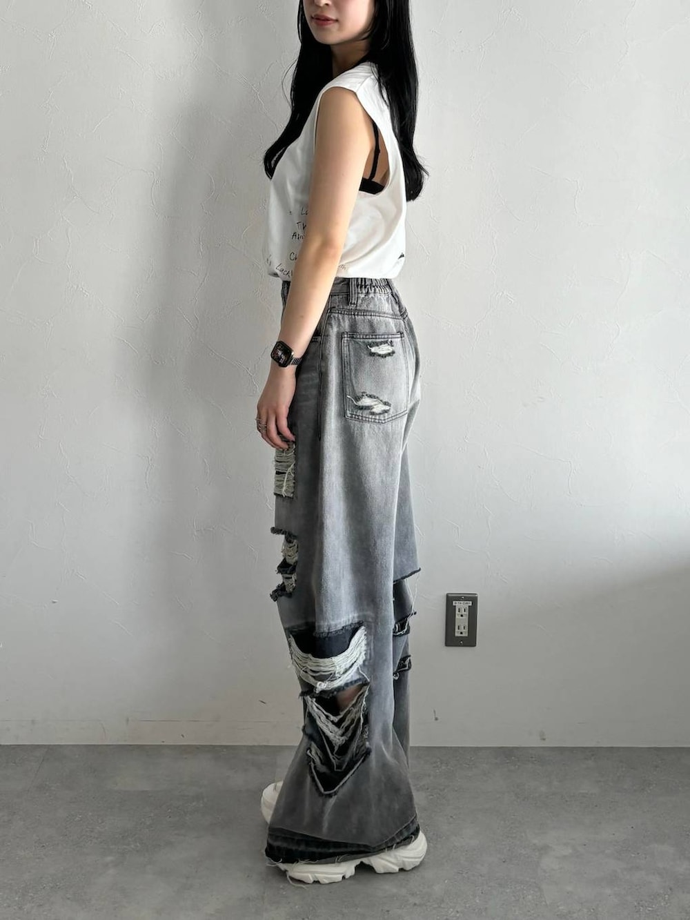 ブラック系のデニムパンツ、ホワイト系のスニーカー、ホワイト系のTシャツ/カットソーを着用したレディースの春コーディネートの3枚目の写真