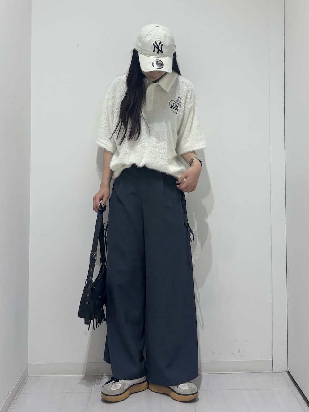 ブラック系のショルダーバッグ、グレー系のスラックス、ホワイト系のポロシャツを着用したレディースの春コーディネートの2枚目の写真