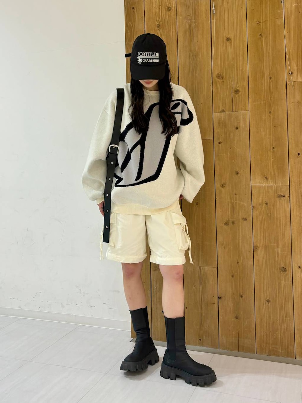 ホワイト系のカーゴパンツ、ブラック系のブーツ、ブラック系のショルダーバッグを着用したレディースの冬コーディネートの2枚目の写真