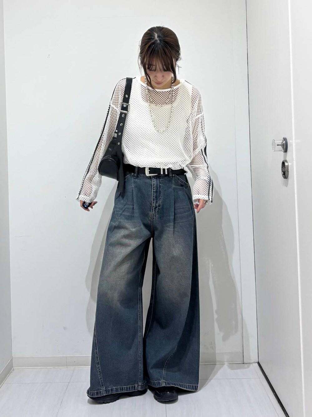 ブルー系のデニムパンツ、ブラック系のスニーカー、ホワイト系のTシャツ/カットソーを着用したレディースの春コーディネートの7枚目の写真